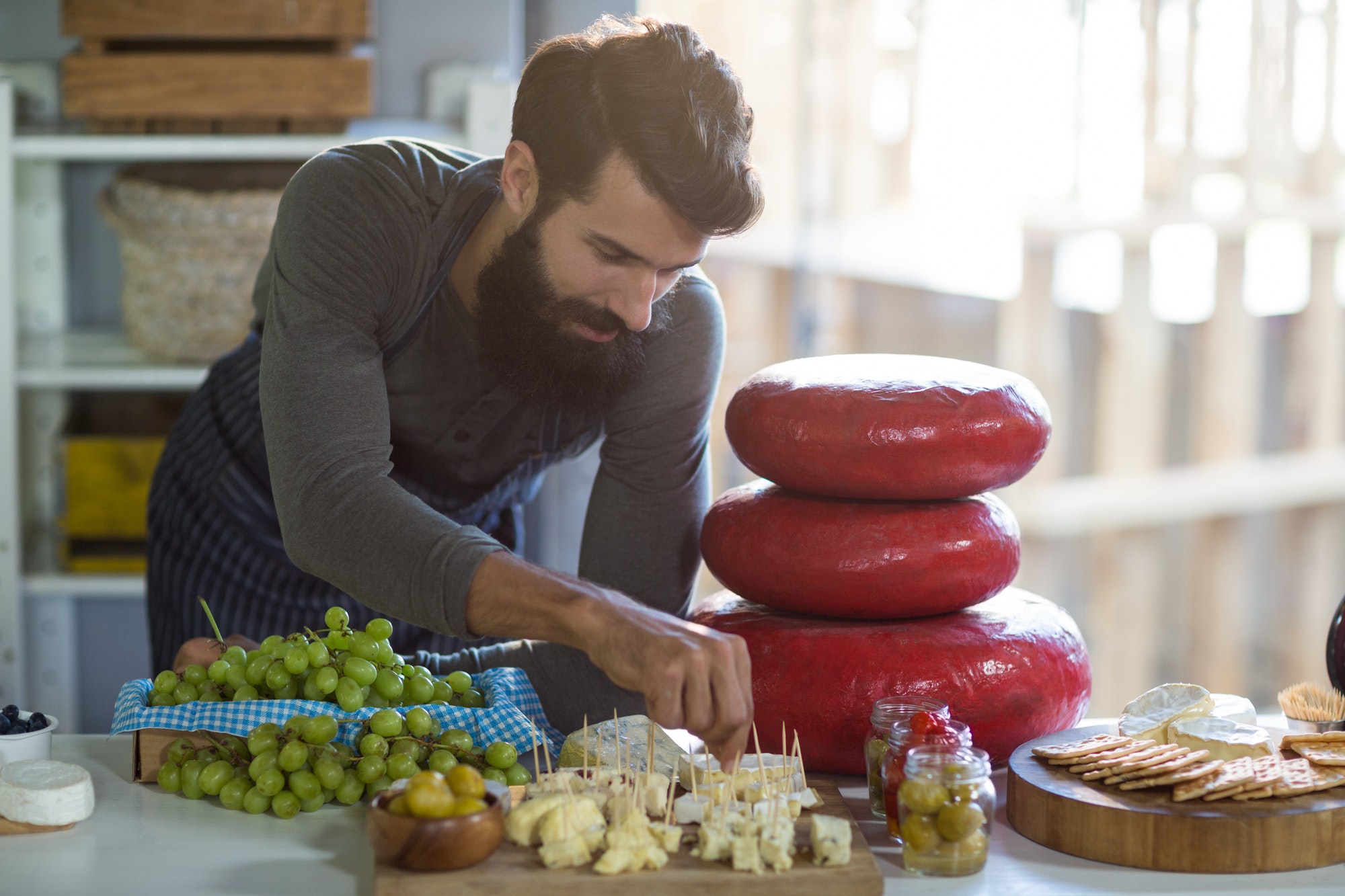 Salesman arranging cheese at counter